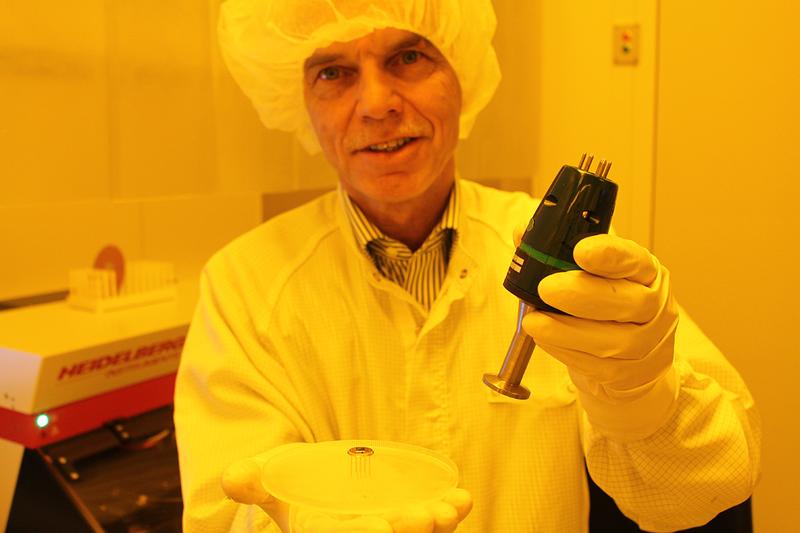 Prof. Dr. Friedemann Völklein mit einem Vakuum-Mikrosensor, der im Vergleich zu einem konventionellen Druck-Messgerät (in der linken Hand) wesentlich kleiner und leistungsfähiger ist.