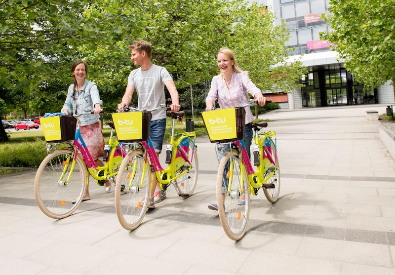 Janina Biell, Thomas Scholze und Charlotte Grzelkowski von der BTU präsentieren die frisch eingetroffenen Fahrräder vor dem BTU-Hauptgebäude am Zentralcampus