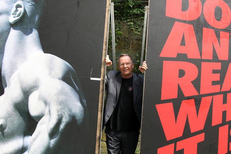 Prof. Uwe Göbel zwischen zwei von ihm gestalteten Plakaten.