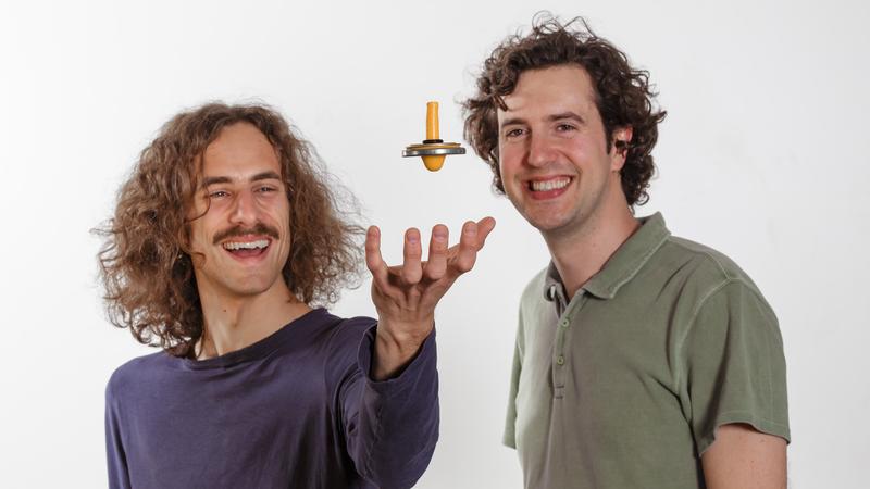 Cosimo Rusconi (li.) und Oriol Romero-Isart (re.) lassen einen Magnetkreisel scheinbar schweben, um ihre Arbeiten zu Nanomagneten zu veranschaulichen.