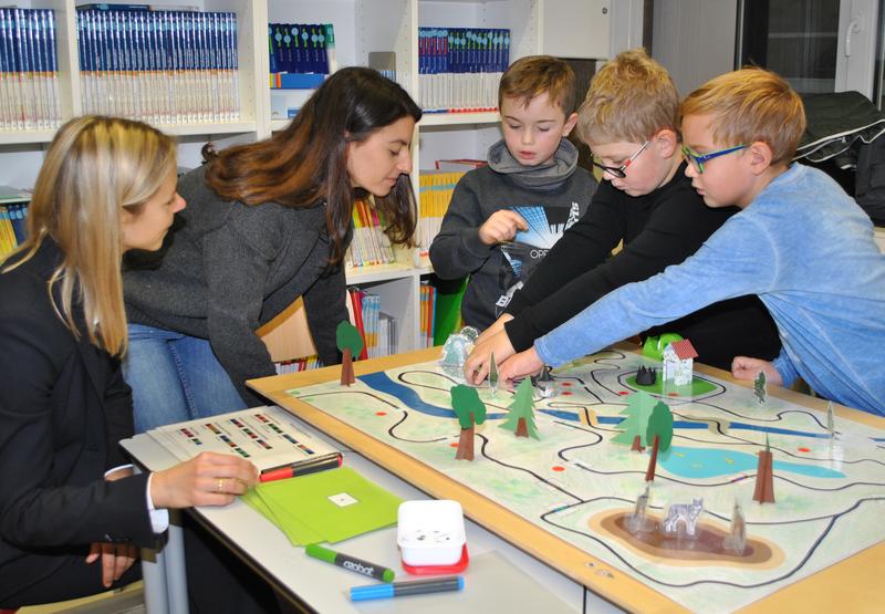 Schüler der Grundschule Heusweiler programmieren einen Mini-Roboter und lassen ihn so verschiedene Abenteuer erleben. Links: Prof. Silke Ladel und Lehramts-Studentin Saina Akhlaghi (2.v.l.).