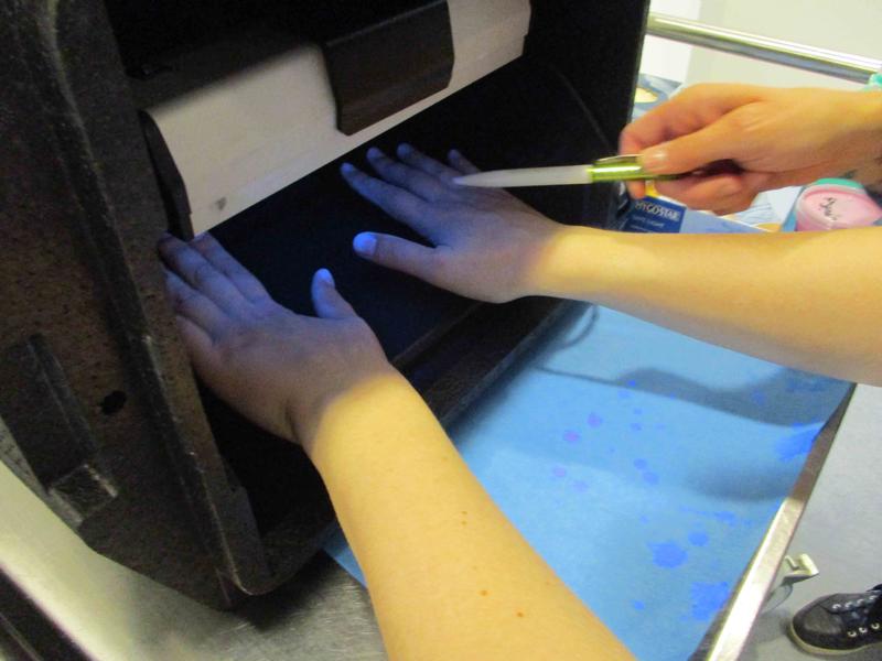 Bei einem Aktionstag der „Aktion Saubere Hände“ am Universitätsklinikum Ulm wird demonstriert, wie mithilfe der UV-Lampe sichtbar gemacht werden kann, ob die Hände korrekt desinfiziert wurden.
