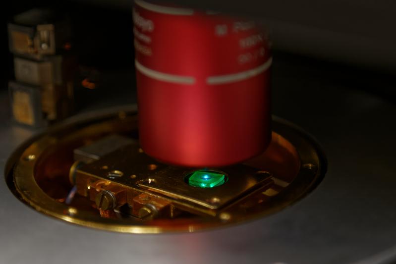 Eine Probe mit mehreren grün leuchtenden Perowskit-Quantenpunkten, die von einem blauen Laser angeregt werden. 
