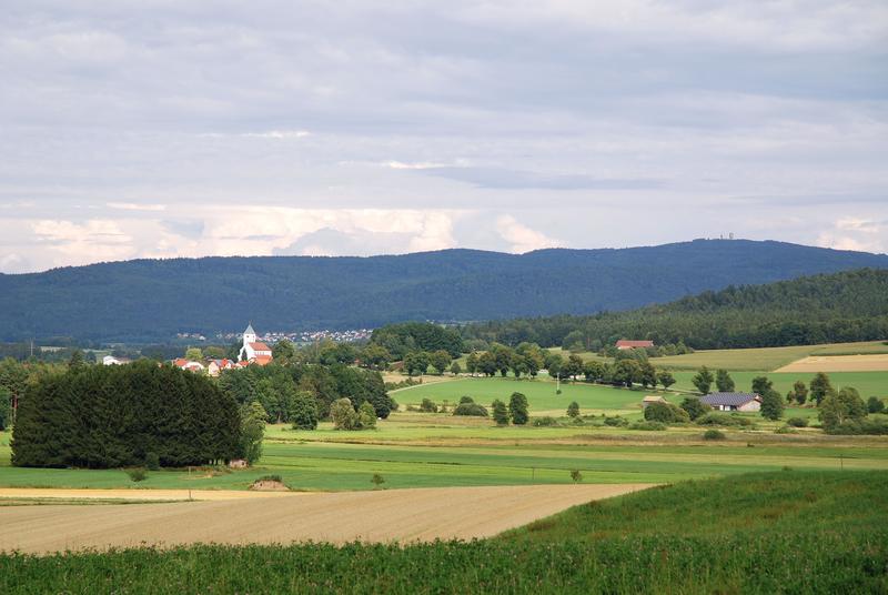 Typisches Foto aus dem Projektgebiet; im Vordergrund die Ortschaft Ast, im Mittelgrund Waldmünchen, im Hintergrund das Grenzgebirge mit dem Čerchov (1042m NN)