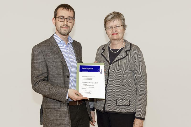 Juliane Besters-Dilger, Prorektorin für Studium und Lehre, überreicht Ingo Henneberg den E-Learning-Förderpreis 2018 der Universität Freiburg.