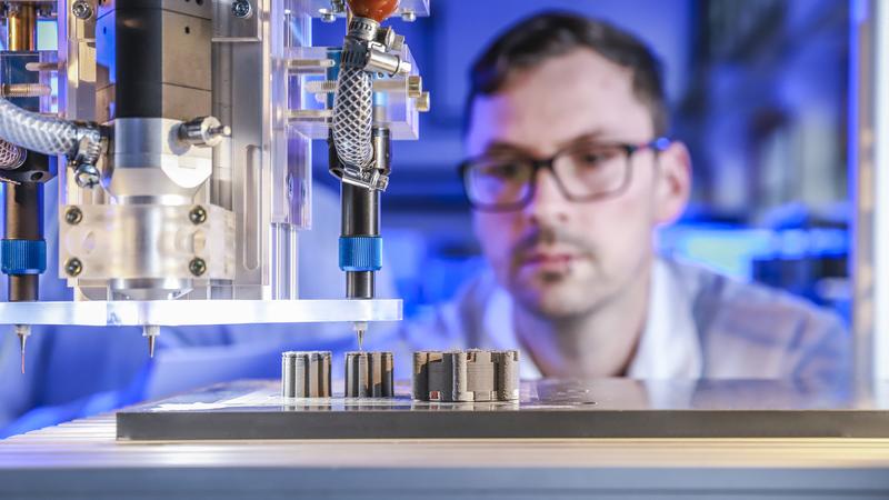 Johannes Rudolph überwacht im Labor den 3D-Multimaterialdruck einer elektrischen Maschine bei dem erstmals Kupfer, Keramik und Eisen gleichzeitig in einem Druckprozess zum Einsatz kommen. 