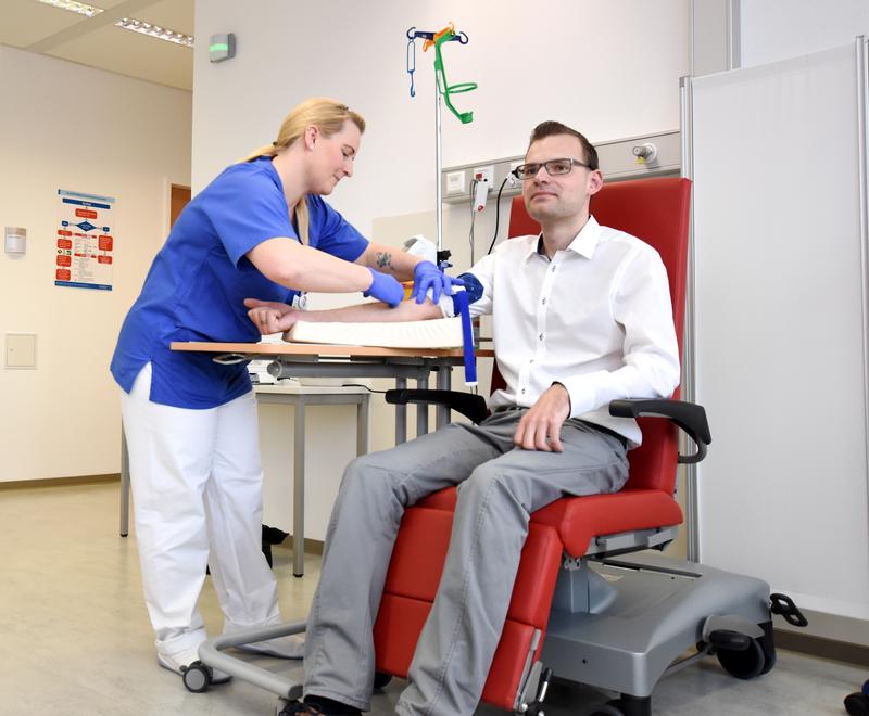 Krankenschwester Anke Schmidt versorgt Patient Benjamin Langer mit einer Infusion.