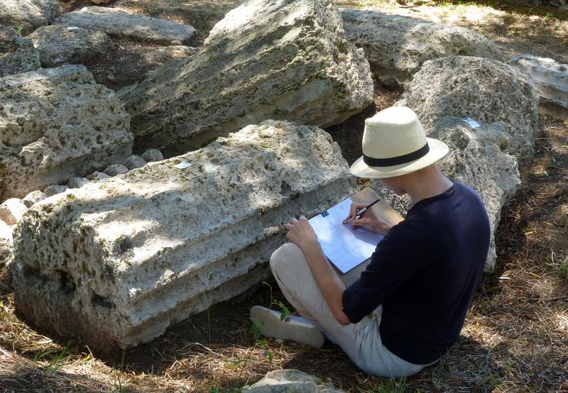 Der Student der Historischen Bauforschung Karol Niwinski bei der zeichnerischen Dokumentation antiker Säulenfragmenten in Olympia, Mitarbeit im Leonidaion-Projekt des DAI.