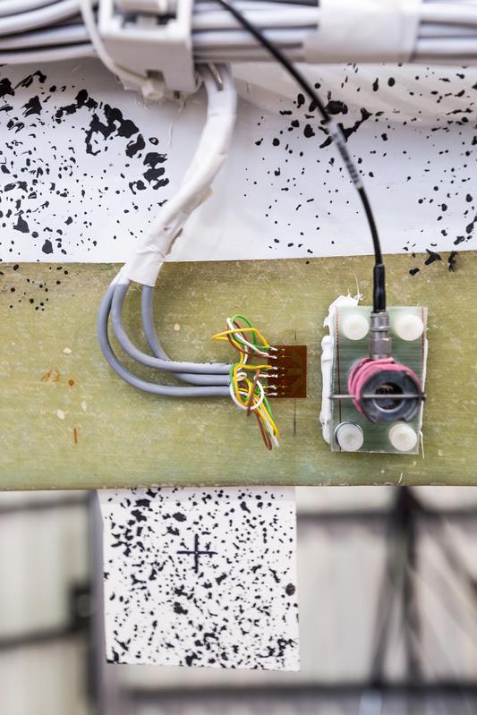 Measurement equipment: strain gauge, acoustic emission sensor and reference marker with speckle pattern for the DIC system.