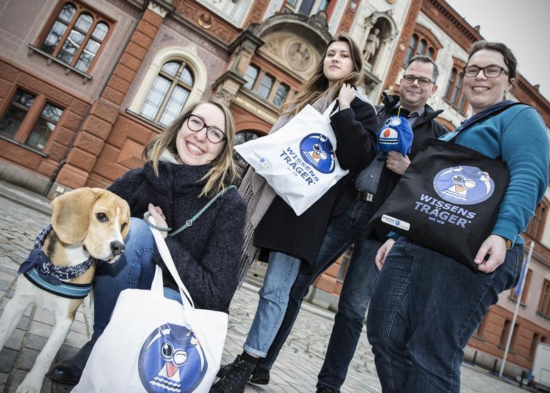 v.l.: A. Jahnke mit Hund Nilsson, D. Kiseleva und R. Geschke (Printzentrum Rostock) sowie D. Kiepsel (Jub.-Team Uni Rostock) mit der Kollektion zum 600. Geburtstag der Universität.