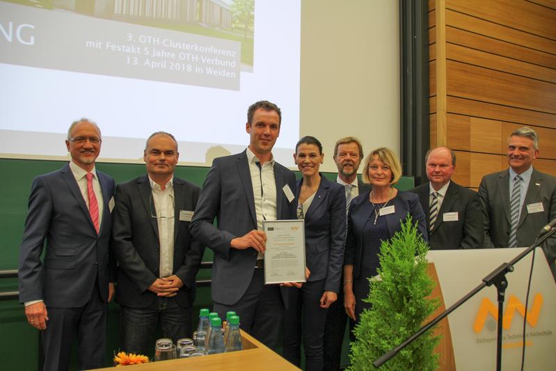 Roland Gömmel (Mitte), Forschungsassistent der OTH Regensburg, erhält die Auszeichnung für seinen Vortrag im Rahmen der OTH-Clusterkonferenz