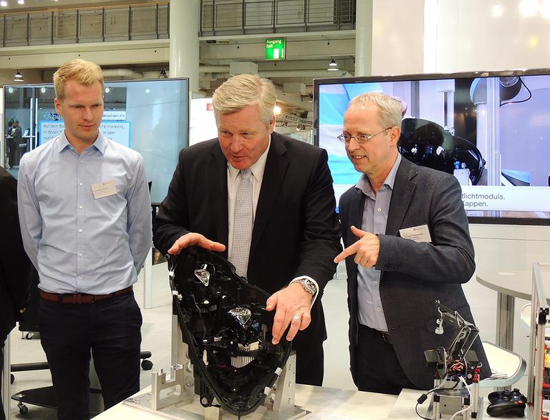 Prof. Dr. Clemens Westerkamp (rechts) erläutert dem Niedersächsischen Wirtschaftsminister Dr. Bernd Althusmann (Mitte) anhand der Montage eines Fahrzeugscheinwerfers die Vorteile der Industrie 4.0.
