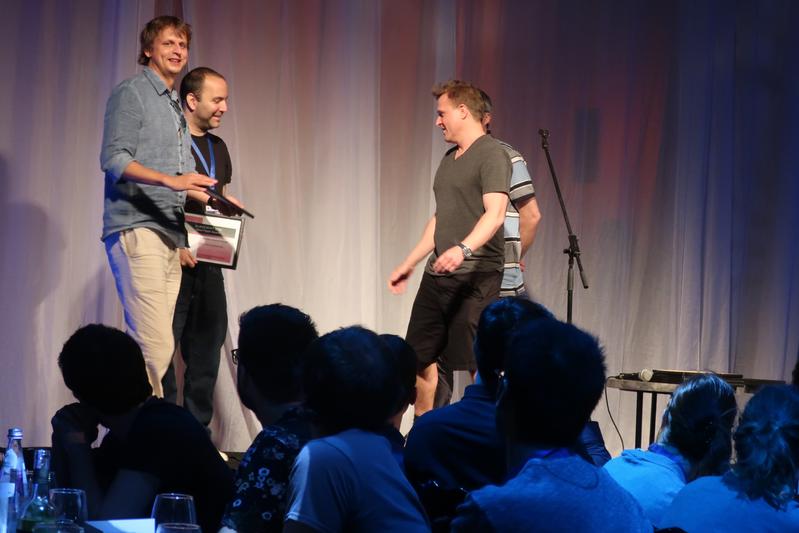 Award ceremony at Eurocrypt 2018: Krzysztof Pietrzak (left) und Bram Cohen (second from left) receive the Best Paper Award from Eurocrypt-chair Jesper Buus Nielsen (right).