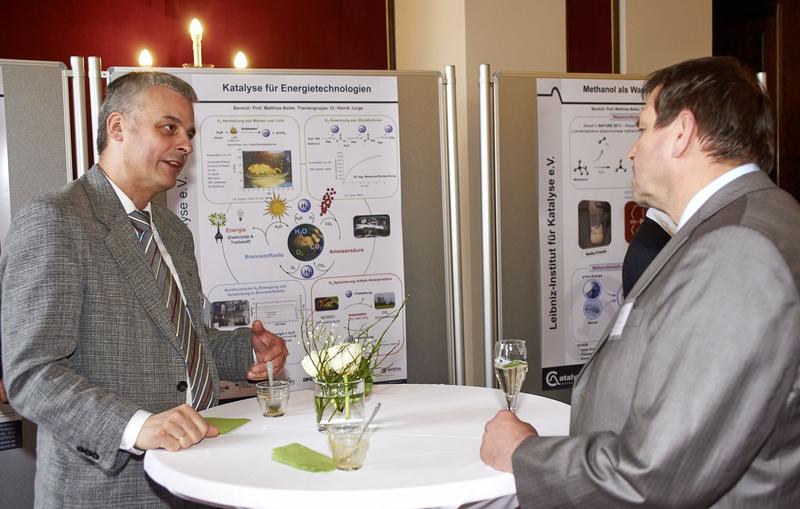 Henrik Junge erklärt einem Besucher des LIKAT Forschungsergebnizze zur Energietechnologie