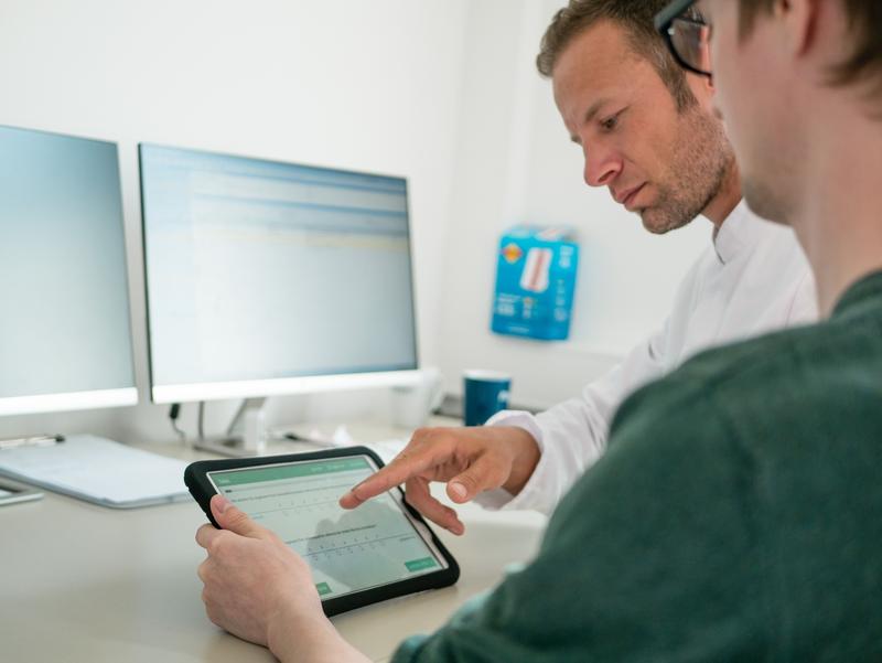 Tablet während der Krebsnachsorge - Dr. Joachim Quandt aus der HNO-Klinik bespricht Angaben mit seinem Patienten