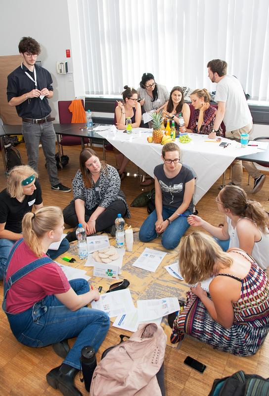 24. UN-Klimakonferenz in Bochum: Die Vertreter der Entwicklungsländer diskutieren bei Reiswaffeln auf dem Boden, die der Industrienationen an reich gedeckten Tischen.