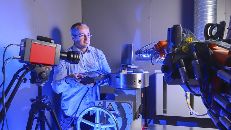 Gerd Paczkowski, wissenschaftlicher Mitarbeiter der Professur Werkstoff- und Oberflächentechnik, richtet den Laserkopf und die Hochgeschwindigkeits-Thermografiekamera auf eine Turbinenschaufel aus.