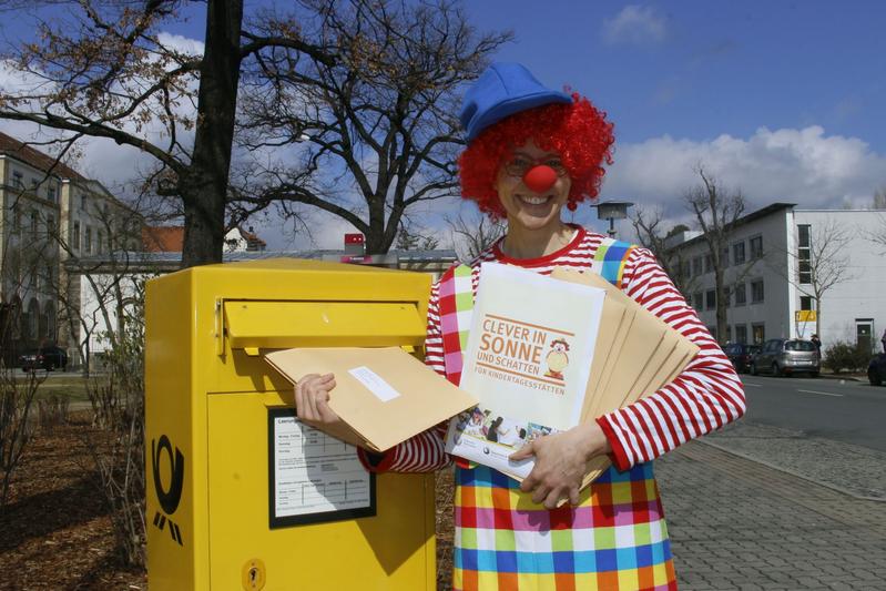 Clown Zitzewitz steckt einige der rund 1.000 Infopakete in den Briefkasten.