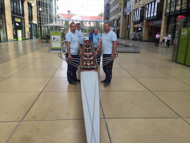 Helfer aus dem Universitätsklinikum Dresden und Bernd Licker vom Dresdner Ruderverein (hinten) positionieren ein Ruderboot im Wasserbecken der Mall des World Trade Centers.