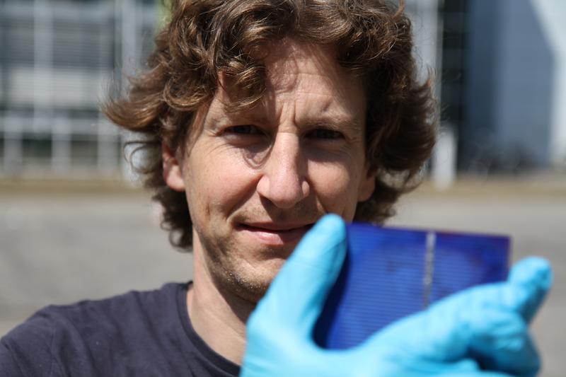 Jun.-Prof. Stefan Weber holding a solar cell 