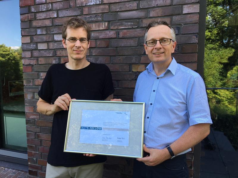HITS Scientific Director Michael Strube (left) presenting the “HITS Fellow” document to Volker Springel (right). 