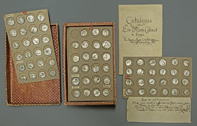 Sammlung römischer und spätantiker Münzen in Wachsabgüssen, die mit Metallfolie umhüllt sind. Die Münztabletts werden mit einem handschriftlichen Katalog in einem Kästchen verwahrt; Ende 18. Jh.