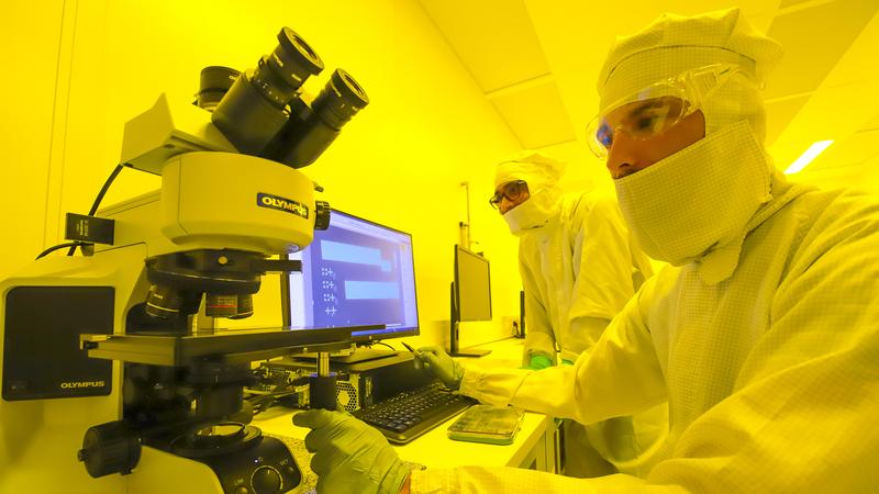 In the lithography area of a cleanroom located within the MAIN building, two researchers of the Professorship of Material Systems for Nanoelectronics use an optical microscope for process control.