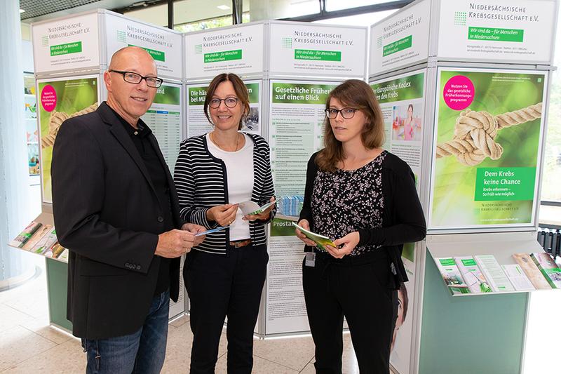 Carsten Pfeil von der Nieders. Krebsgesellschaft, Prof. Dr. Anke Franzke, ärztl. Leiterin des Claudia von Schilling-Zentrums, und Stefanie Seipke, Zentrumskoordinatorin, vor der Ausstellung