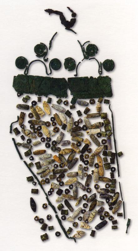 Eiserne Fibel mit Anhänger aus Bronze und Glas- sowie Beinperlen. Aus der Grube 1 der „Tomba della Regina“.