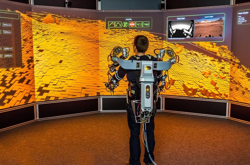 Ein Operator steuert mithilfe eines Oberkörper-Exoskeletts einen Roboter in Utah (USA) von einem virtuellen Leitstand am DFKI in Bremen. 