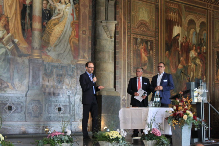 Personen von li. nach re.: Florian Wieduwilt (Gewinner des Posterwettbewerbs), Olaf Heuer (Vertreter der Sparkasse Hildesheim Goslar Peine / Sponsor des Posterwettbewerbs), Tobias Schossig (Vorsi