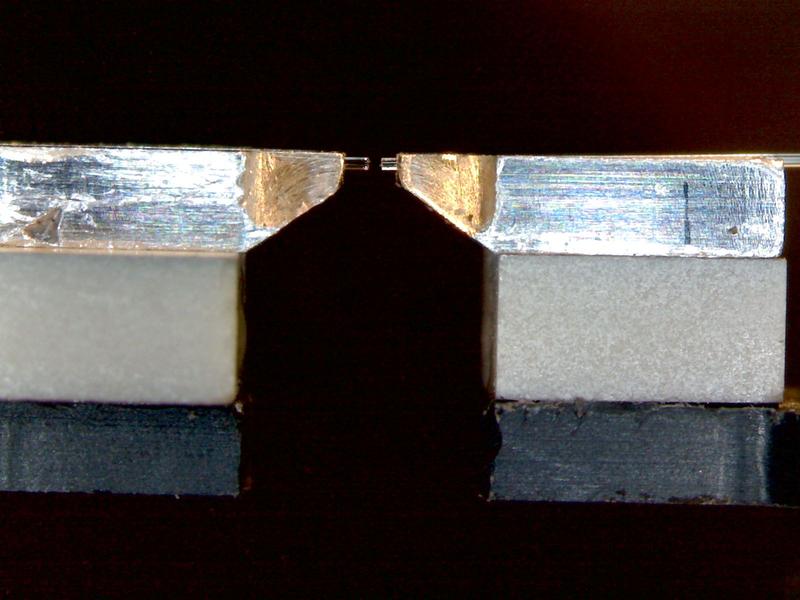 Das Bild zeigt die beiden Glasfasern (Mitte oben). Ihre Enden sind verspiegelt, so dass sie einen so genannten Resonator bilden. Zwischen ihnen wird das Rubidium-Atom eingebracht.