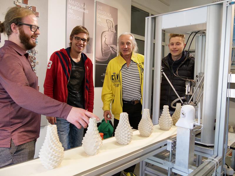 Prof. Jürgen Walter, HsKA (2. v. r.), Diplom-Produktdesigner Fabian Schmid, HfG (1. v. l.) und die Studierenden Julian Schweizerhof und Maximilian Mantel neben dem automatisierten 3D-Keramik-Drucker