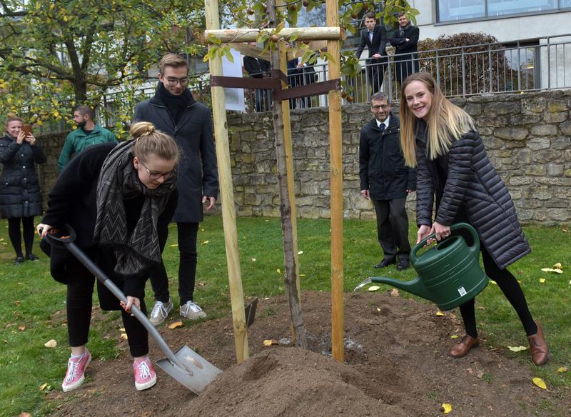 Theologie-Erstsemester Pauline Machnik (r.) sowie die Jura-Erstsemester Vinzenz Richter und Anna Nevraeva (l.) pflanzen gemeinsam mit Präsident Walter Rosenthal den Baum für die Matrikel 2018/19.