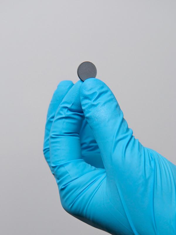 Das mattgraue Pellet ist ein sogenannter geschichteter Kupfer-Eisen-Perowskit, ein Kristall. Es hat auf einer Fingerspitze Platz.