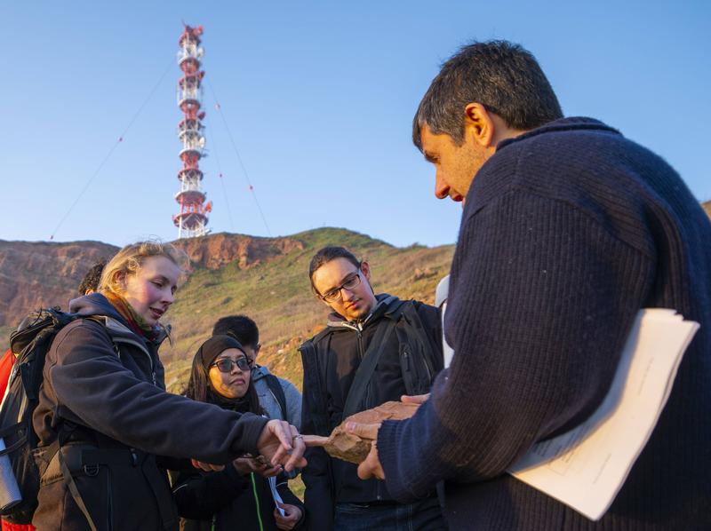  Professor Vikram Unnithan shows students a piece of the reddish rock from which the famous Helgoland rock "Lange Anna" is made. 