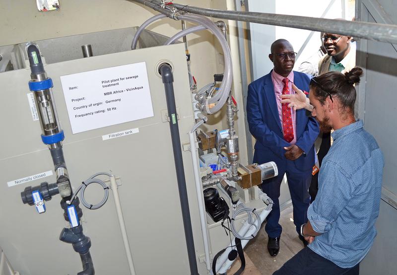 Ephraim Gukelberger (re.), wissenschaftlicher Mitarbeiter der Hochschule Karlsruhe, demonstriert den Membranbioreaktor bei der Inbetriebnahme der Pilotanlage am 23. November 2018 in Kisumu, Kenia