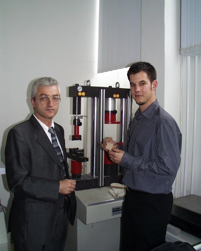 Prof. Ghanem (li.) und Dipl.-Ing.(FH) Frank Gerdesmeier an der Prüfmaschine, wo Lehmwürfel auf ihre Druckfestigkeit getestet werden.