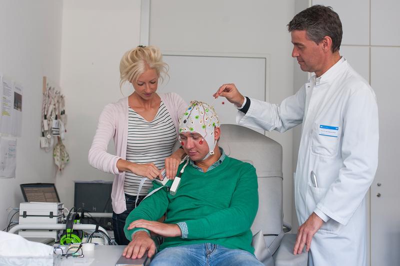 Laura Tiemann, Erstautorin der neuen Studie zur Schmerzwahrnehmung, bereitet zusammen mit Markus Ploner, Heisenberg-Professor für Human Pain Research an der TUM, eine Person für die EEG-Messung vor.