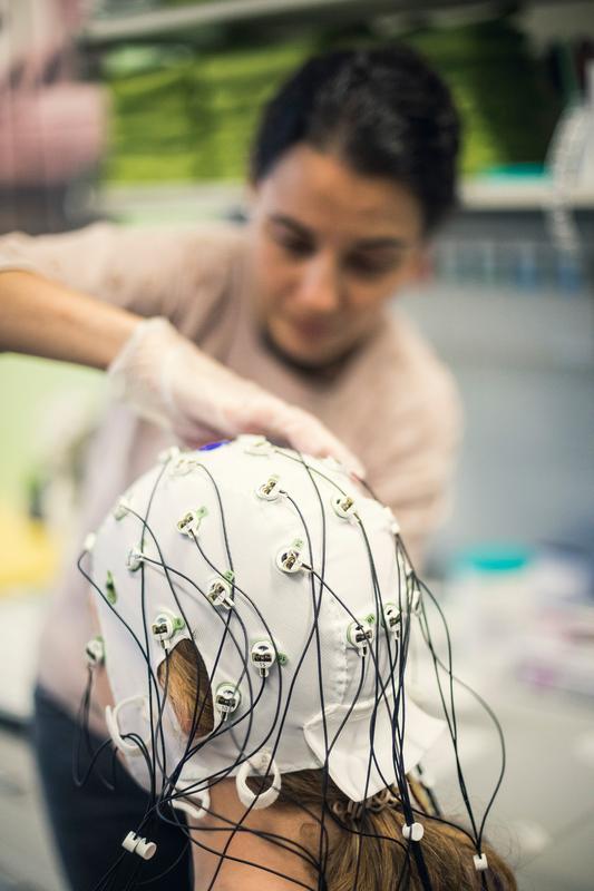 Dunja Kunke setzt der Probandin eine EEG-Haube 