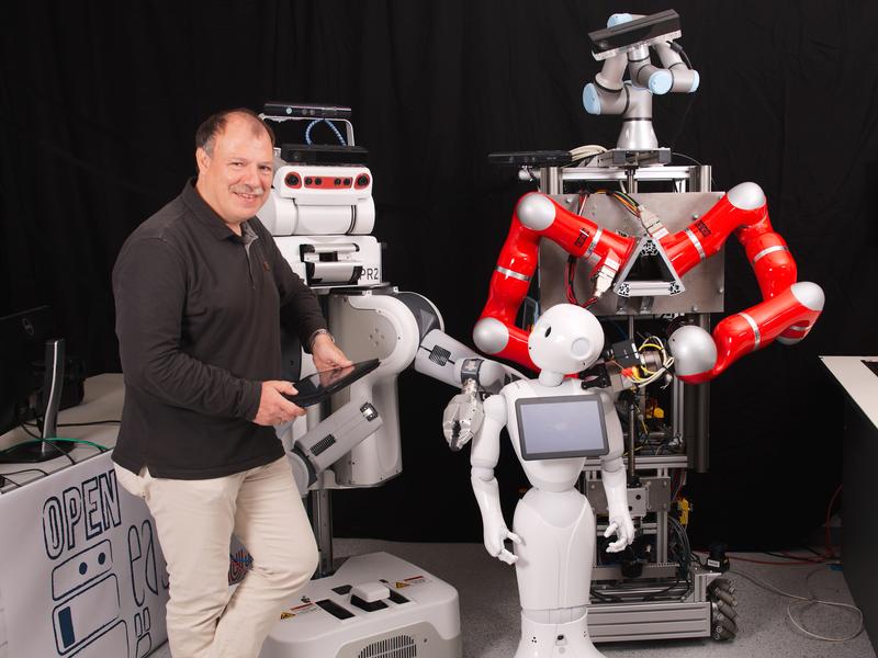 Professor Michael Beetz und seine aktuellen Roboter Raphael (weiß), Boxy (rot) und Pepper (im Vordergrund), die er zu effizienten Helfern ausbilden will.