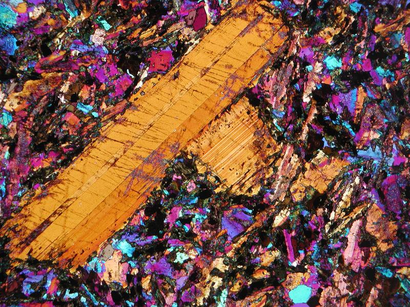 Mikroskopische Aufnahme basaltischen Ganggesteins in einem Dünnschliff. Das Gestein besteht überwiegend aus kalziumreichem Feldspat. Die Bildweite beträgt fünf Millimeter.