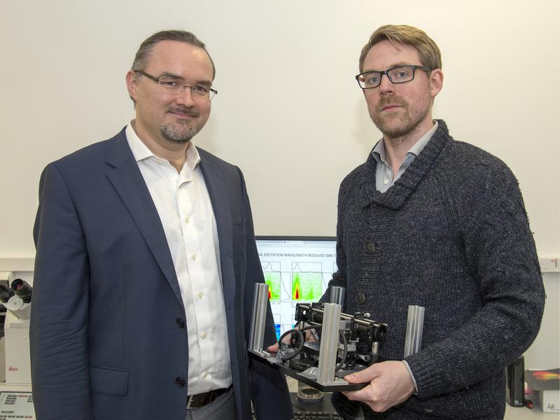 Prof. Dr. Juergen Hauer (li) und Erstautor Erling Thyrhaug mit ihrem Messinstrument. Im Hintergrund Spektren, die damit aufgenommen wurden. 