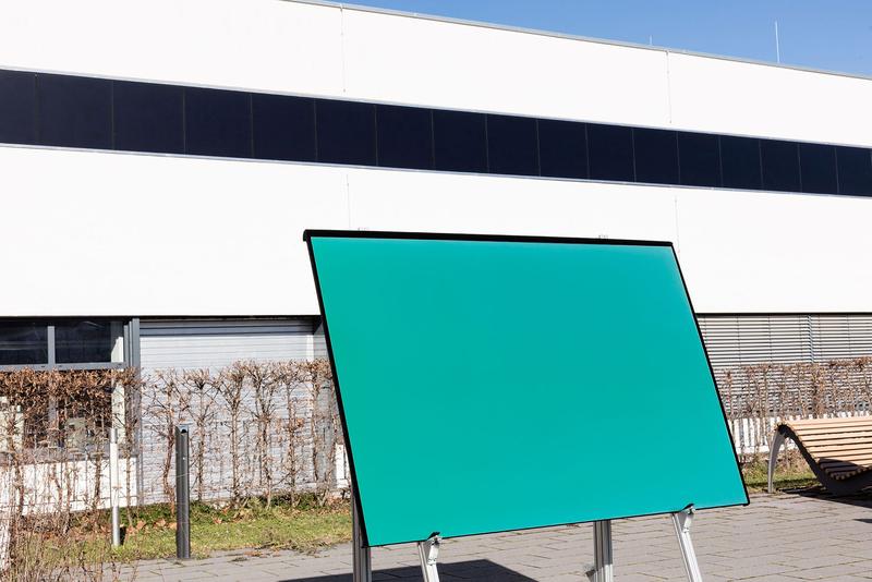 In die Fassade des Gebäudes sind Solarmodule mit 210 Wp Leistung integriert. Würde man diese in grün – wie im Vordergrund – herstellen, hätten sie 195 Wp, also 93% der Leistung des schwarzen Moduls.