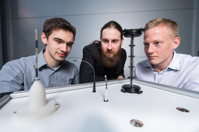 Die Doktoranden Dominik Scholtes (l.), Rouven Britz und Yannik Goergen (r.) aus Prof. Stefan Seeleckes Team mit Prototypen der biegsamen Roboterarme, die auf der Hannover Messe zu sehen sein werden.