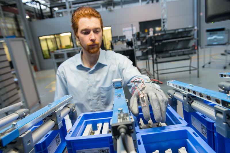 Doktorand Sebastian Gratz-Kelly aus dem Forscherteam von Professor Stefan Seelecke demonstriert den Prototyp des Handschuhs, der auf der Hannover Messe zu sehen sein wird.