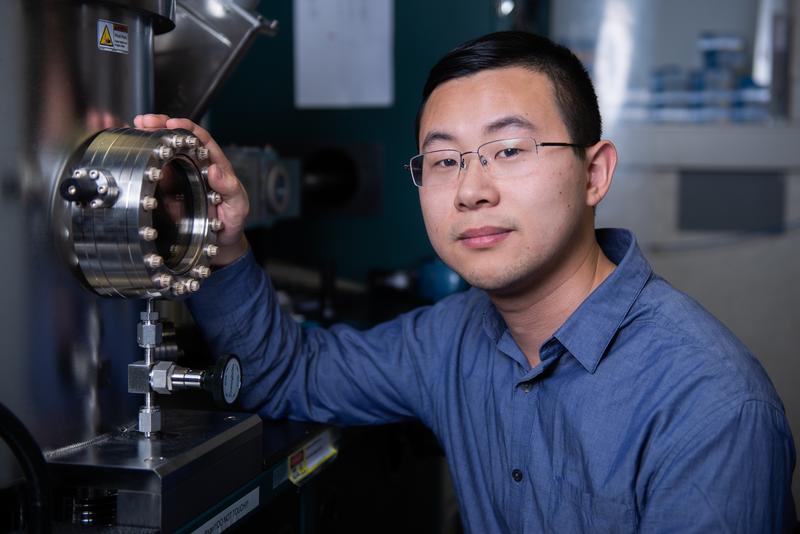 Zhaochu Luo, Hauptautor der Studie, vor einer sogenannten Sputter-Depositions-Apparatur. In der Vorrichtung werden die Schichten aus Platin, Kobalt und Aluminiumoxid erzeugt. 