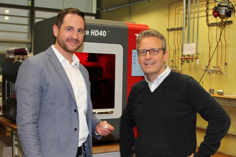 Unternehmensgründer Dr. Andreas Baum (l.) und Mentor Professor Dr. Carlo Burkhardt vor ihrem neu entwickelten LMM-Metalldrucker, der hochpräzise Metallbauteile drucken kann