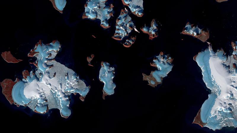 Schmelzende Gletscher in der Russischen Arktis. Die Gletscher (blau) auf den rot-braunen Inseln sind nur wenig mit Schnee bedeckt, was ein sicheres Zeichen für starke Massenverluste ist. 