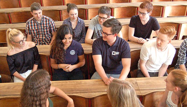 Schülerinnen und Schüler umringen zwei Studierende bei den Tandem-Tagen an der Uni Würzburg.